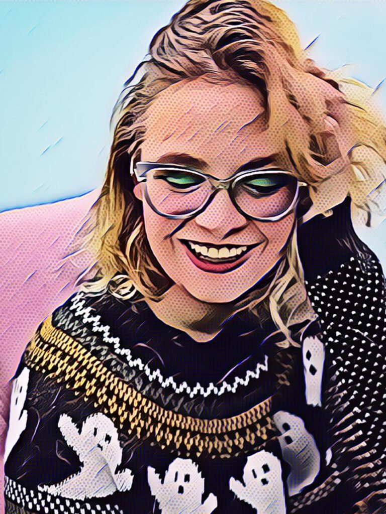 A cartoonified image of a person with blond, wavy hair sitting on a pink recliner. They are wearing glasses and a black sweater with ghosts on it.